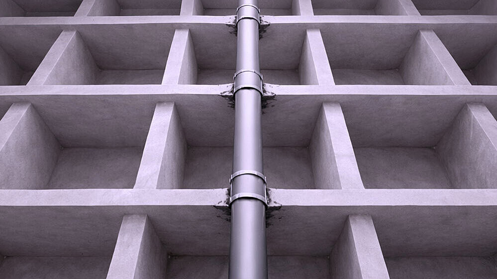 Schematyczna ilustracja rury przebiegającej w górę przez kilka stropów.